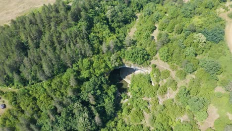 Pedestal-drone-shot-revealing-the-opening-of-the-cave's-entrance,-a-natural-rock-arch-called-the-Gods-Bridge,-located-near-Vratsa,-in-Bulgaria