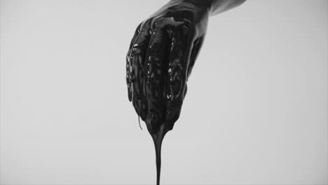 Mano-Humana-Cubierta-De-Pintura-Negra-Oscura-Goteando-En-Movimiento-Inverso-Subiendo-Hacia-La-Mano-Con-Una-Toma-Estática-De-Fondo-Blanco