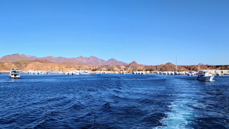 Sailing-ocean-POV-mountain-beach-water-ships-at-Egypt-Sharm-El-Sheikh-coastline-slow-motion-waves,-coastal-lifestyle