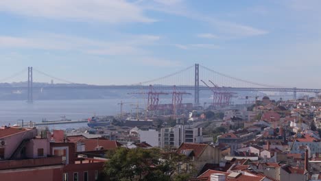 Ascenso-Aéreo-Sobre-La-Densa-Población-De-Viviendas-En-Lisboa,-Portugal,-Para-Establecer-Grúas-Portuarias-Y-Un-Puente-Colgante.