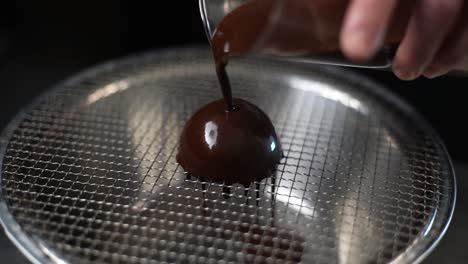 Slow-motion-clip-of-chef-pouring-melted-chocolate-glaze-over-scoop-of-ice-cream