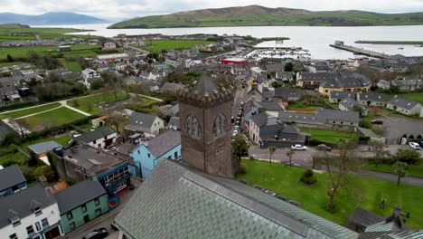 Dingle-Ireland-church-steeple-drone-shot-with-church-tower-in-foreground-and-harbor-behind