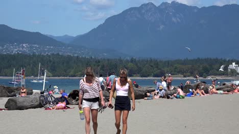 Zwei-Junge-Frauen-Gehen-An-Einem-Sonnigen-Strand-Auf-Die-Kamera-Zu