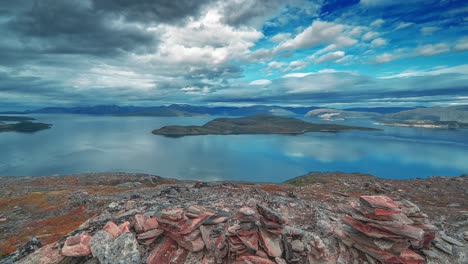 Wirbelnde-Sturmwolken-Im-Gegenlicht-Der-Sonne-Ziehen-Im-Zeitraffervideo-über-Den-Ruhigen-Fjord-Und-Die-Berge