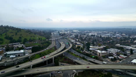 Aerial-drone-fly-above-highway-roundabout-intersection,-walnut-creek-california-skyline-city-town-in-American-hillside