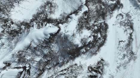 Top-down-shot-above-Japans-Myoko-mountain-summit-peak,-camera-flying-above-snowy-cliff-edge