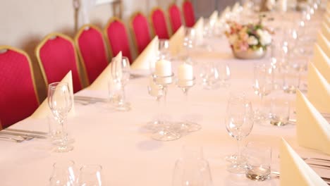 Young-attractive-woman-sitting-down-alone-next-to-a-big-and-beautiful-event-dinner-table-celebration