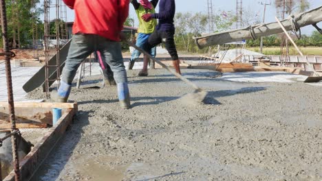 A-group-of-construction-workers-are-pouring,-mixing-and-spreading-a-mixture-of-sand,-gravel-and-cement-for-the-construction-of-a-house-in-Chachoengsao,-Thailand