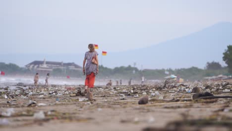 Los-Turistas-Caminan-Por-La-Costa-De-Kuta-Bali,-A-Pesar-De-Que-Hay-Montones-De-Basura,-Plástico-Y-Botellas.