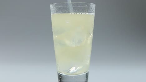 Fixed-shot-of-fizzy-drink-being-poured-into-a-clear-glass-with-ice