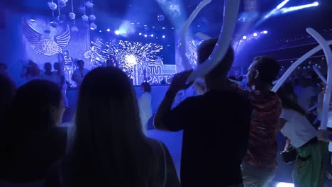 Crowd-holding-balloons-and-dancing-to-live-DJ-music-under-vibrant-club-lights