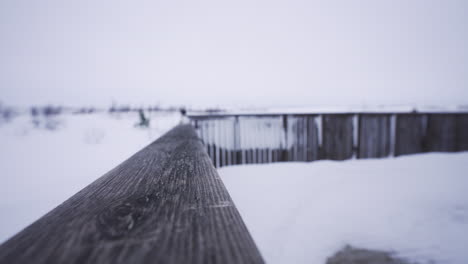 Established-wooden-frozen-fence-in-winter-snowy-white-storm-landscape