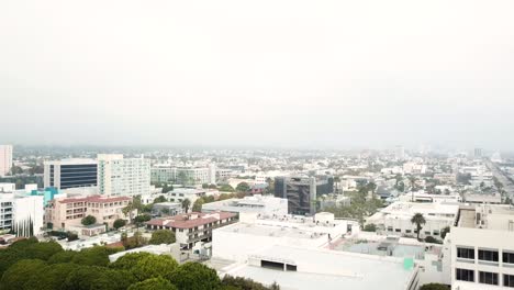 Panning-Aerial-View-of-Downtown-Santa-Monica,-Los-Angeles,-California-on-a-nice-day-with-Skyscrapers-and-Palm-Trees-in-the-background