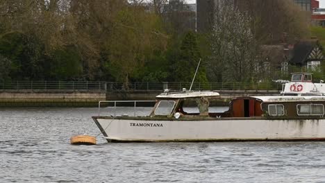 Boat-sailing-past-TRAMONTANA-on-the-Thames-in-London,-United-Kingdom