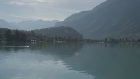 Eine-Ente-In-Der-Ferne-Schwimmt-Ruhig-Mit-Perfekter-Aussicht-Auf-Den-Malerischen-Hafen,-Während-Die-Wellen-Folgen-|-Ländlicher-Europäischer-Berghang-Mit-Großem-See