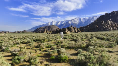 Aerial-view-around-an-astronaut-walking-across-desert-nature-in-a-space-suit