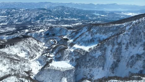 Drone-shot-from-above-snowy-mountain-summit,-camera-pushing-forwards-and-panning-upwards