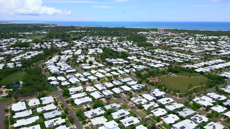 Aerial-Drone-of-Muirhead-Darwin-NT-Australia-White-Roof-Homes-with-Solar-Panels-and-Ocean-in-Distance,-Orbit