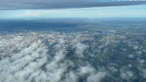 Aerial-view-from-an-airplane-cabin-of-Bordeaux-city-an-Garonne-river,-in-a-sunny-day-with-some-low-clouds