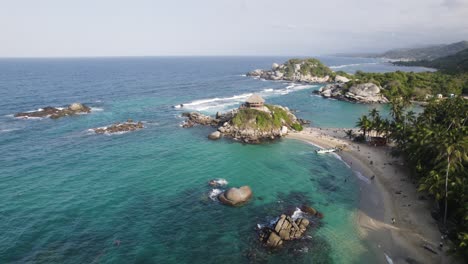 Aerial-parallax-shot-of-Tayrona-National-Park-with-large-rocks-on-sea-in-Colombia