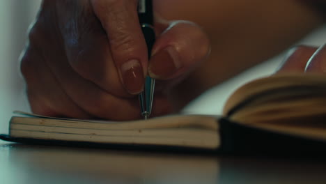 close-up-of-senior-woman-right-hands-writing-a-book-notebook-journal