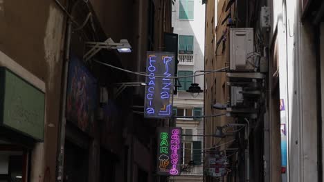 Clip-En-Cámara-Lenta-Que-Se-Desplaza-Desde-Los-Letreros-De-Neón-A-Lo-Largo-De-Un-Callejón-Estrecho-Hasta-La-Gente-Que-Pasa-Caminando