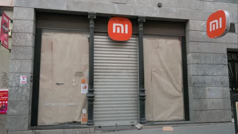 Los-Peatones-Pasan-Por-Una-Multinacional-China-Cerrada-De-Tecnología-Y-Electrónica,-La-Tienda-Insignia-De-Xiaomi-En-Madrid,-España