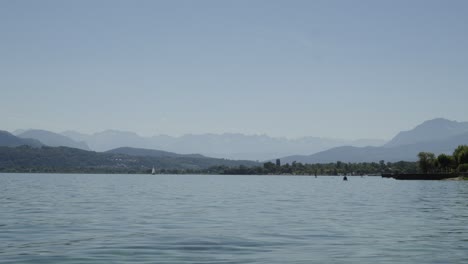 Cisnes-Y-Gente-Haciendo-Kayak-En-El-Lago-Bourget-Francia-Agua-Costera-Lapso-De-Tiempo-Aves-Nadando-Y-Turistas-Disfrutando-Al-Aire-Libre-Ciudad-Balneario-En-Saboya