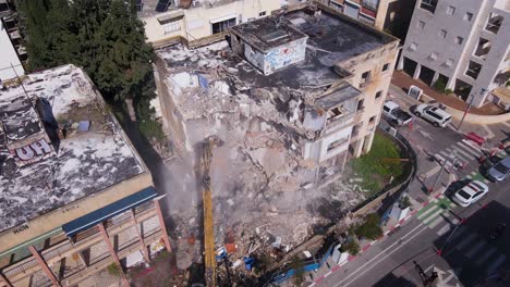 Demolition-of-an-Old-Building-Using-a-Long-Armed-Excavator-in-Tel-Aviv-Jaffa,-Israel---Aerial-Drone-Shot