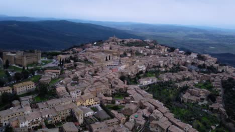 Vista-Aérea-Del-Hermoso-Pueblo-En-La-Cima-De-Una-Colina,-Ciudad-Medieval-De-Montalcino-En-Italia