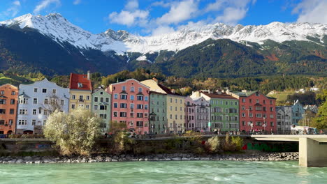 Innsbruck-Austria-colorful-pastel-buildings-capital-Tyrol-Tyrolean-Alps-mountain-backdrop-the-bridge-over-the-Inn-River-cars-bikes-people-sunny-blue-sky-clouds-October-November-autumn-fall-static-shot