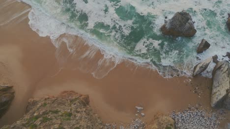 Secluded-Atlantic-ocean-sand-beach-surrounded-by-cliffs-and-breaking-waves