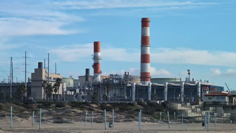 Closeup-panoramic-shot-of-orange-and-white-stripped-industrial-towers-at-los-angeles-california,-industrial-background-and-street-daylight-motion