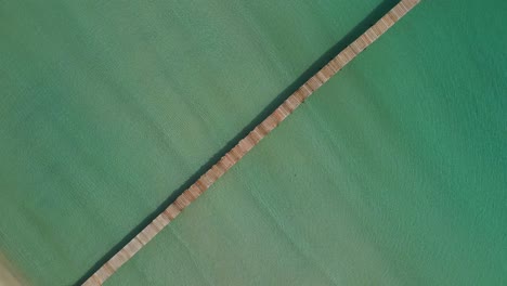 Muro-Beach,-Mallorca,-creative-spinning-drone-shot-of-iconic-wooden-dock-bird's-view