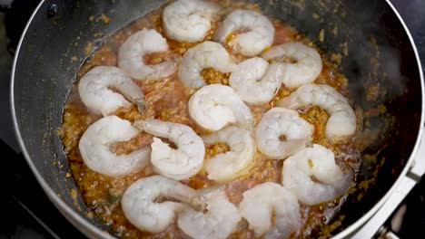 Persona-Añadiendo-Delicadamente-Gambas-A-Una-Salsa-Caliente-Y-Burbujeante-En-Un-Plato,-Capturada-En-Cámara-Lenta,-Mostrando-Experiencia-Culinaria-Y-El-Placer-De-Cenar.