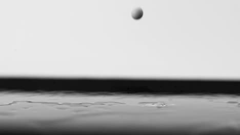 Round-Black-Drops-Splashing-in-Dense-White-Liquid-Ripples,-close-up