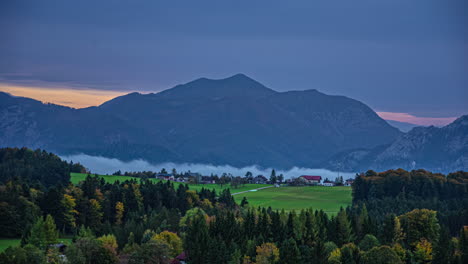 Zeitraffer,-Rosa,-Goldene-Skyline-Wolken-Ziehen-In-Den-österreichischen-Alpen,-Ländliches-Tal,-Grüne-Wiese,-Berghintergrund