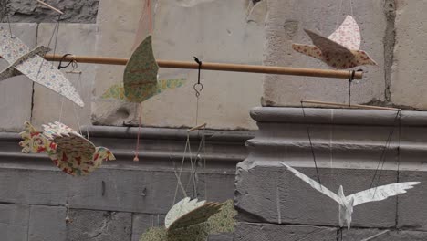 Close-up-shot-of-patterned-models-of-birds-on-display-in-market,-moving-gently-in-the-breeze