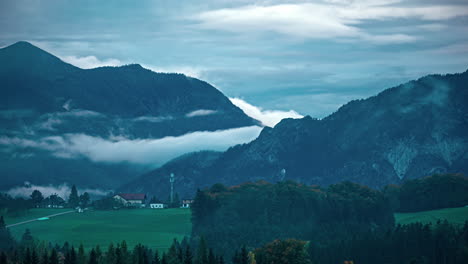 Clouds-moving-around-Austrian-mountain-rural-green-fields-alps-skyline-village-small-town-in-rural-agricultural-valley
