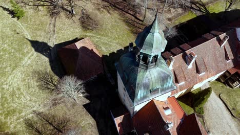 Aerial-drone-fly-above-Castle-Tower-in-countryside-neighbourhood-at-north-eastern-europe-during-dry-autumn-landscape-with-dry-trees-and-red-tile-roof-houses