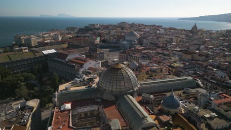 Aerial-Pullback-Away-from-Piazza-del-Plebiscito,-Galleria-Umberto-I-with-Mediterranean-Sea-in-Background