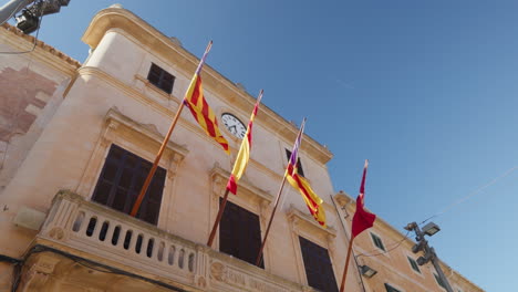 Historical-town-hall-building-with-waving-flags-in-Santanyi,-Mallorca