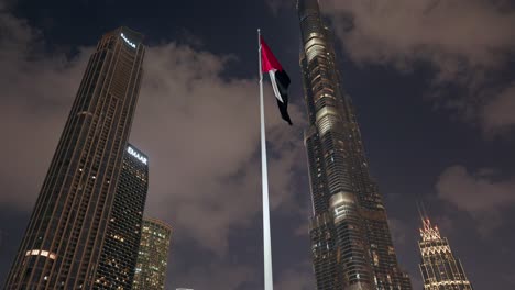 Tilt-shot-of-the-Dubai-skyline-featuring-the-Burj-Khalifa,-with-the-UAE-flag-flying-proudly