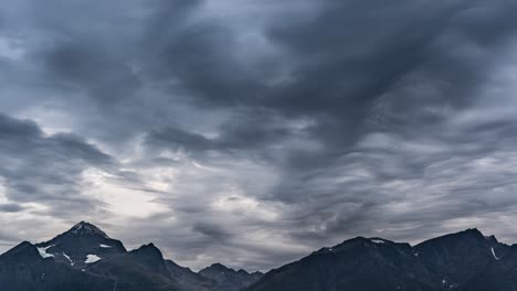 Stürmische-Wolken-Im-Gegenlicht-Der-Sonne-Ziehen-Am-Himmel-über-Den-Dunklen-Bergen-Vorbei