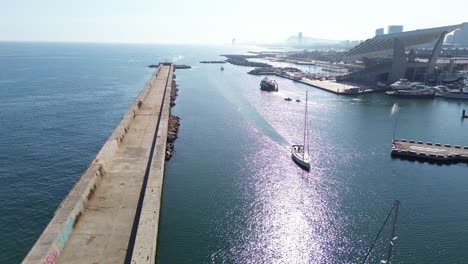 Drone-shot-of-a-sailboat-entering-the-port-of-Barcelona-on-a-sunny-day