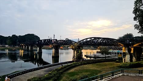 Vista-Del-Atardecer-Del-Histórico-Puente-Sobre-El-Río-Kwai,-Que-Se-Hizo-Famoso-Por-Una-Película-Adaptada-De-La-Realización-Del-Ferrocarril-De-La-Muerte-Que-Conectó-Myanmar-Y-Tailandia-Durante-La-Segunda-Guerra-Mundial.