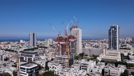 David-Bloch-St-with-Construction-cranes-above-buildings,-panoramic-aerial-establish