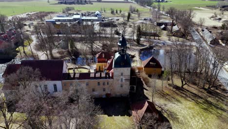 Panorámica-Antigua-Casa-Torre-Patrimonial-En-El-Noreste-De-Europa,-Pueblo,-Paisaje-Rural-Letón,-Drone-Aéreo-Estableciendo-Toma