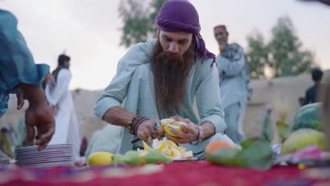 Hombre-Paquistaní-De-Barba-Larga-Cortando-Frutas-Para-Ramadán-Iftar-En-Khuzdar,-Pakistán