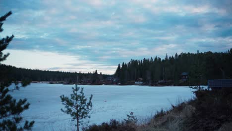 Cloudy-Sunset-Sky-Over-Frozen-Lake-In-Rural-Farm-Landscape-In-Norway